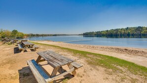 Un espace de pique-nique au bord du lac, équipé de bancs et de tables en bois.