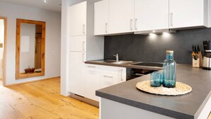 Een moderne keuken met witte kasten, een donkere spatwand en een houten vloer.