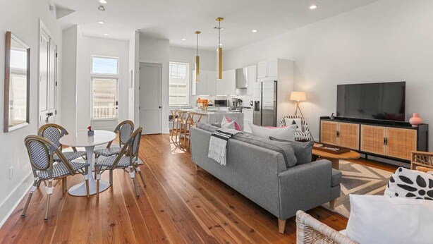 A modern apartment with a dining area, kitchen, living room, and a TV.