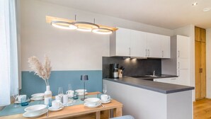 Eine moderne Küche mit weißen Schränken, einer schwarzen Arbeitsplatte und einer Holztruhe.
