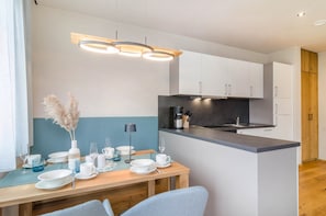 Una cocina moderna con armarios blancos, encimera negra y una isla de madera.