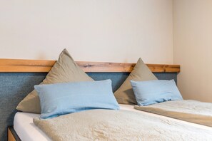 Una cama con cabecera de madera, dos almohadas y una colcha.