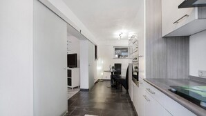A modern kitchen with dark tiles, white cabinetry, and a dining area with a table and chairs. - Apartment 'Fewo Nele' with Wi-Fi (Gries)
