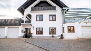 A two-story house with a balcony, a garage, and a paved driveway. - Apartment 'Fewo Nele' with Wi-Fi (Gries)