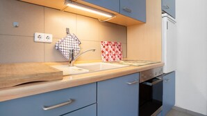 Een keuken met een houten aanrecht, een gootsteen, een fornuis en kastjes.