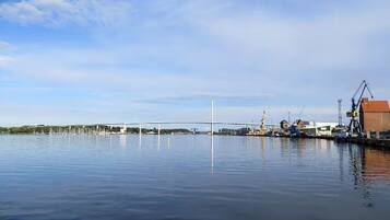 A calm waterfront with a bridge, cranes, and industrial buildings.