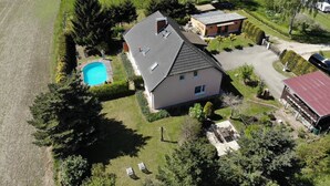 Een huis met een zwembad, een garage en een omheind erf.