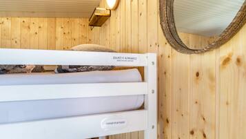 A wooden room with a bunk bed labeled 'SCHLAFEN IN ALPAKAWOLLE' and a mirror on the wall.