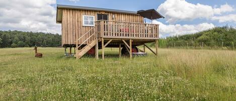 A wooden cabin with a deck, a window, and a door.