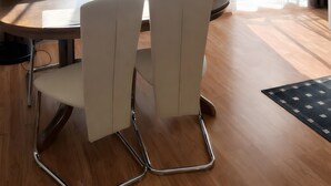 Ein Essbereich mit einem runden Tisch, vier Stühlen, einer Pendelleuchte und einem gerahmten Bild an der Wand.