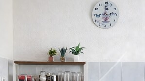 Eine Küche mit Mikrowelle, Wasserkocher, Kaffeemaschine und einer Uhr an der Wand.