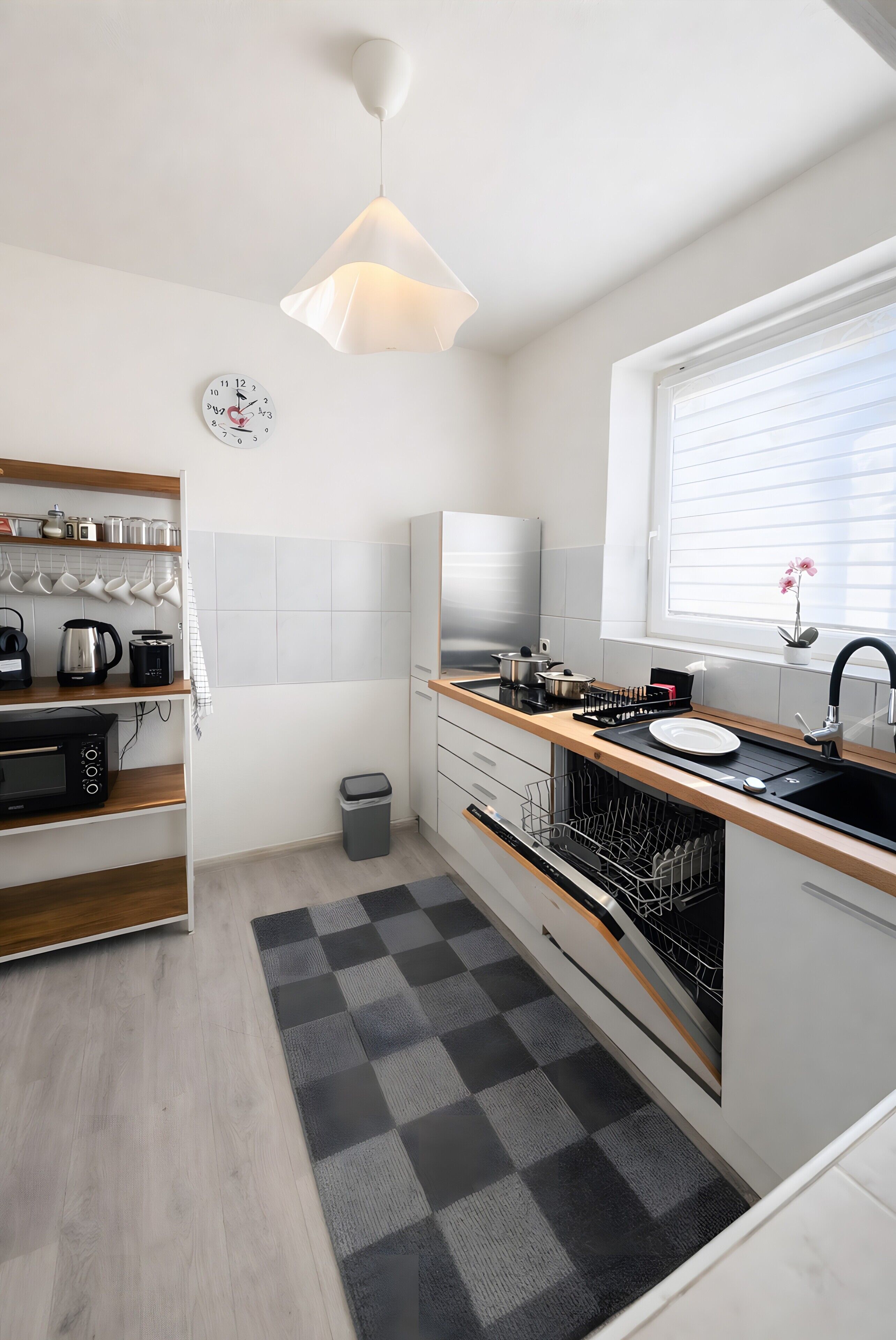 Eine moderne Küche mit Backofen, Spüle und einem Fenster mit Jalousien.