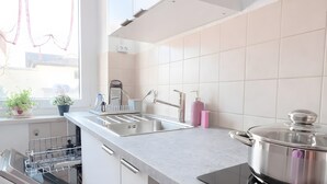 A modern kitchen with white cabinetry, a built-in oven, a stovetop, and a window with a view. - Apartment 'Dream Home' with Balcony and Wi-Fi (Friedrichshafen)