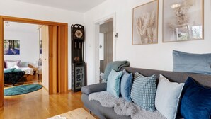 Ein Wohnzimmer mit einer Couch, Kissen, einer Uhr und gerahmten Kunstwerken.