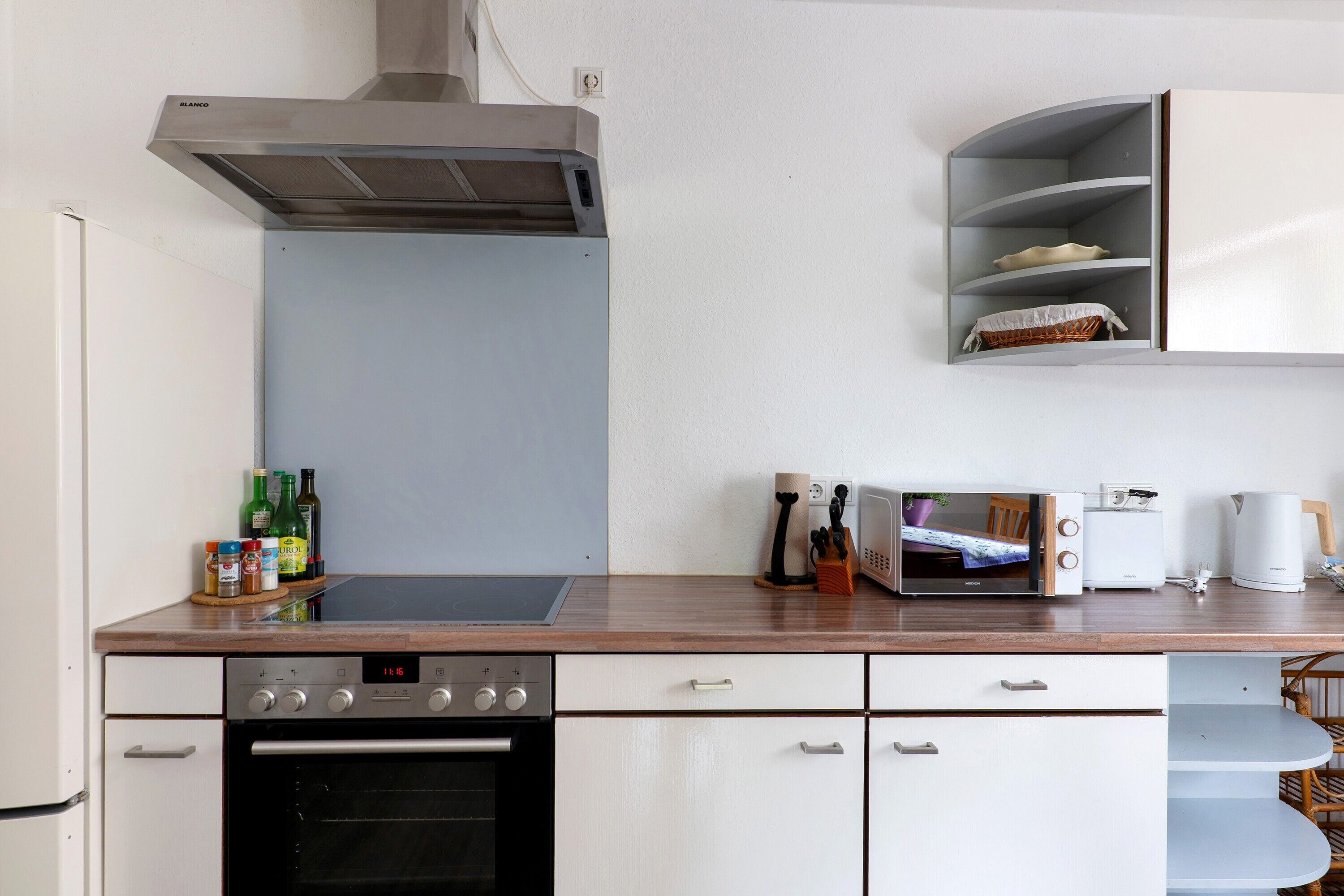 A kitchen with a stove, oven, microwave, and a built-in cabinet above the counter.