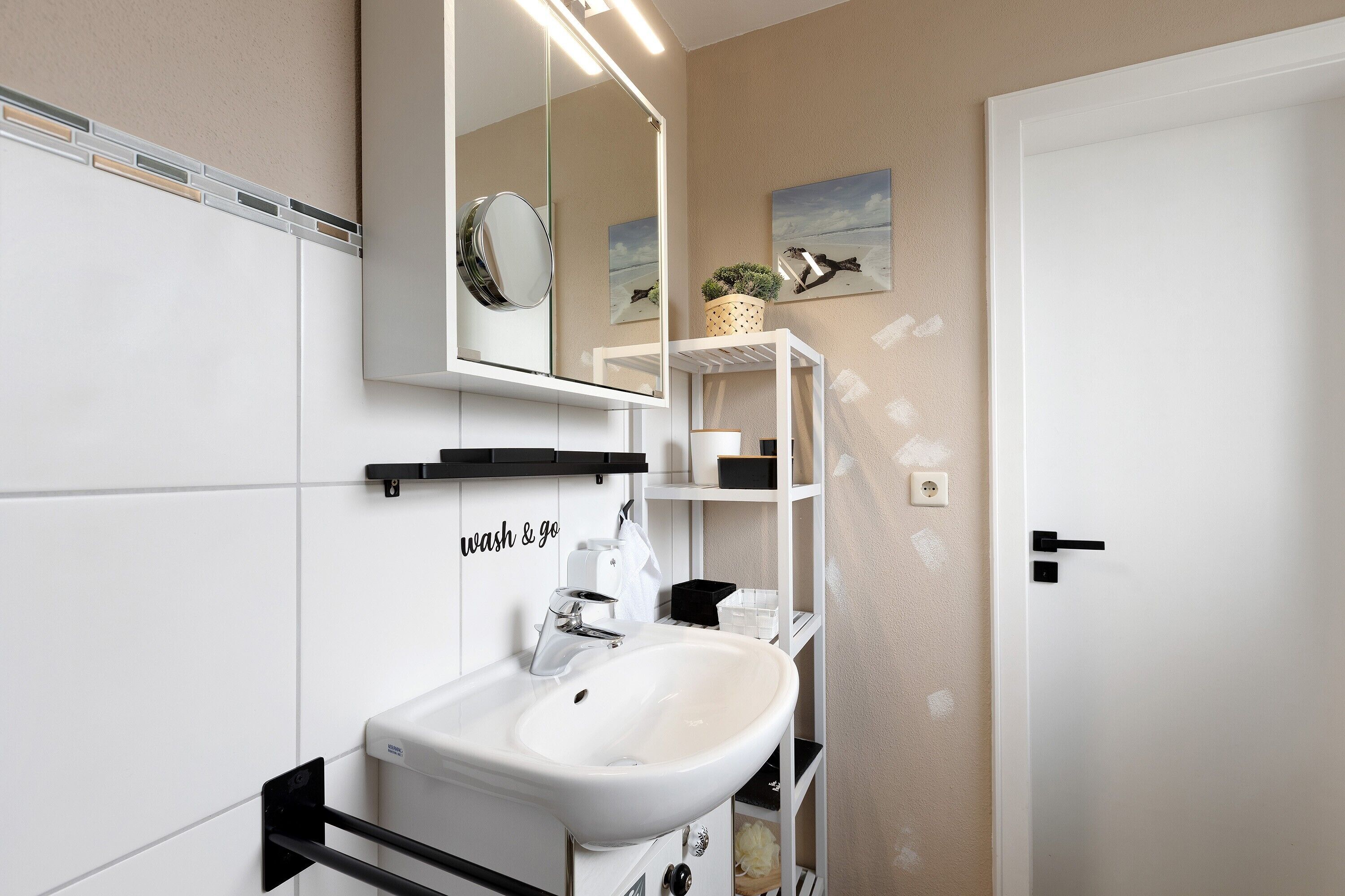 A bathroom with a white sink, mirror, and shelves with toiletries.