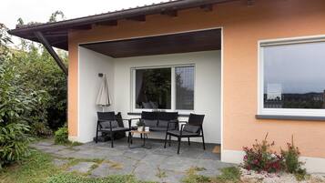 Un edificio moderno con un patio que tiene asientos al aire libre y un ventanal grande.