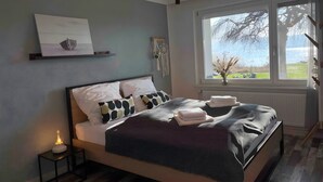 Ein modernes Schlafzimmer mit Bett, Nachttisch und einem Fenster mit Blick.