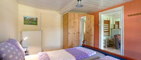 Un dormitorio con dos camas, ventilador de techo, radiador y un cuadro en la pared.