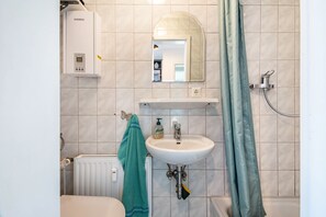 Ein Badezimmer mit Waschbecken, Spiegel, Dusche und Handtuchhalter.