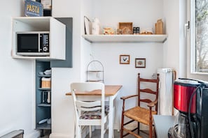 A kitchen with a microwave, a coffee maker, a shelf with kitchen items, and a chair. - Holiday Home 'Harmonie Tiny House' (Oyten)
