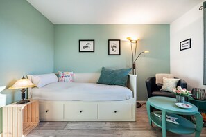 Ein Schlafzimmer mit Bett, Nachttisch, Lampe, Stuhl und Wandbildern.
