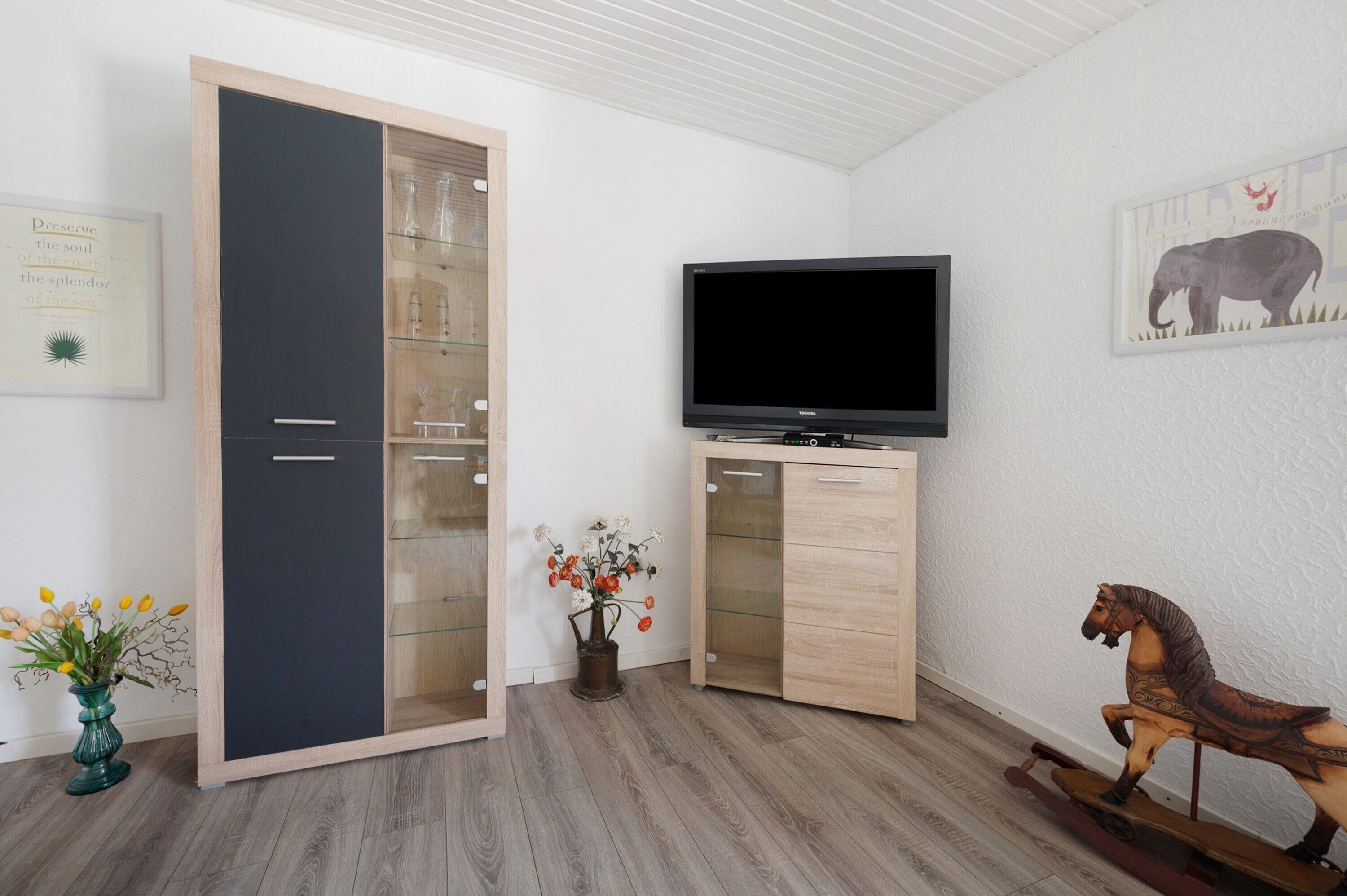 Een kamer met een kledingkast, een televisie, een decoratief paard en een vaas met bloemen.