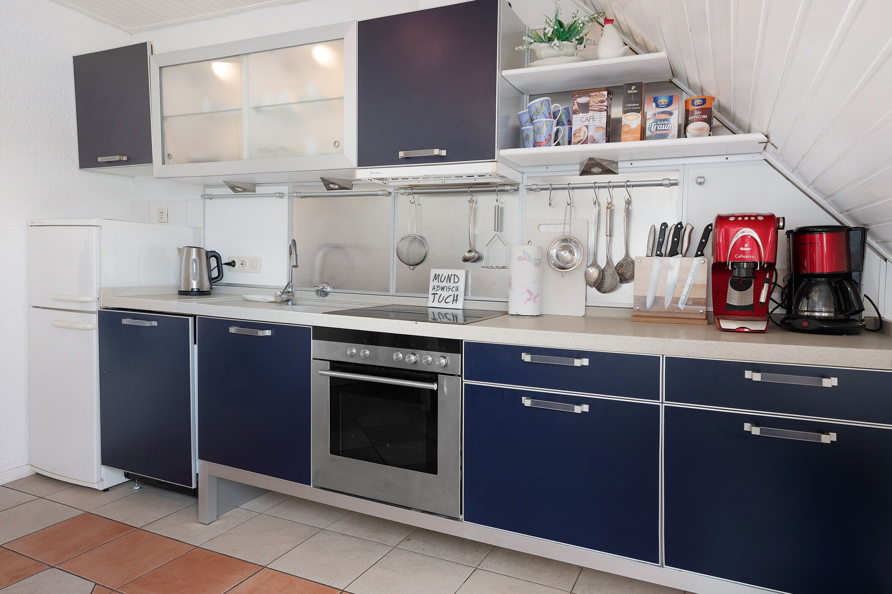 A modern kitchen with stainless steel appliances, a coffee machine, and a variety of utensils.