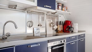 A kitchen with a stainless steel sink, a coffee maker, and a sign that says 'ROUND THE HOUSE TOCK.'