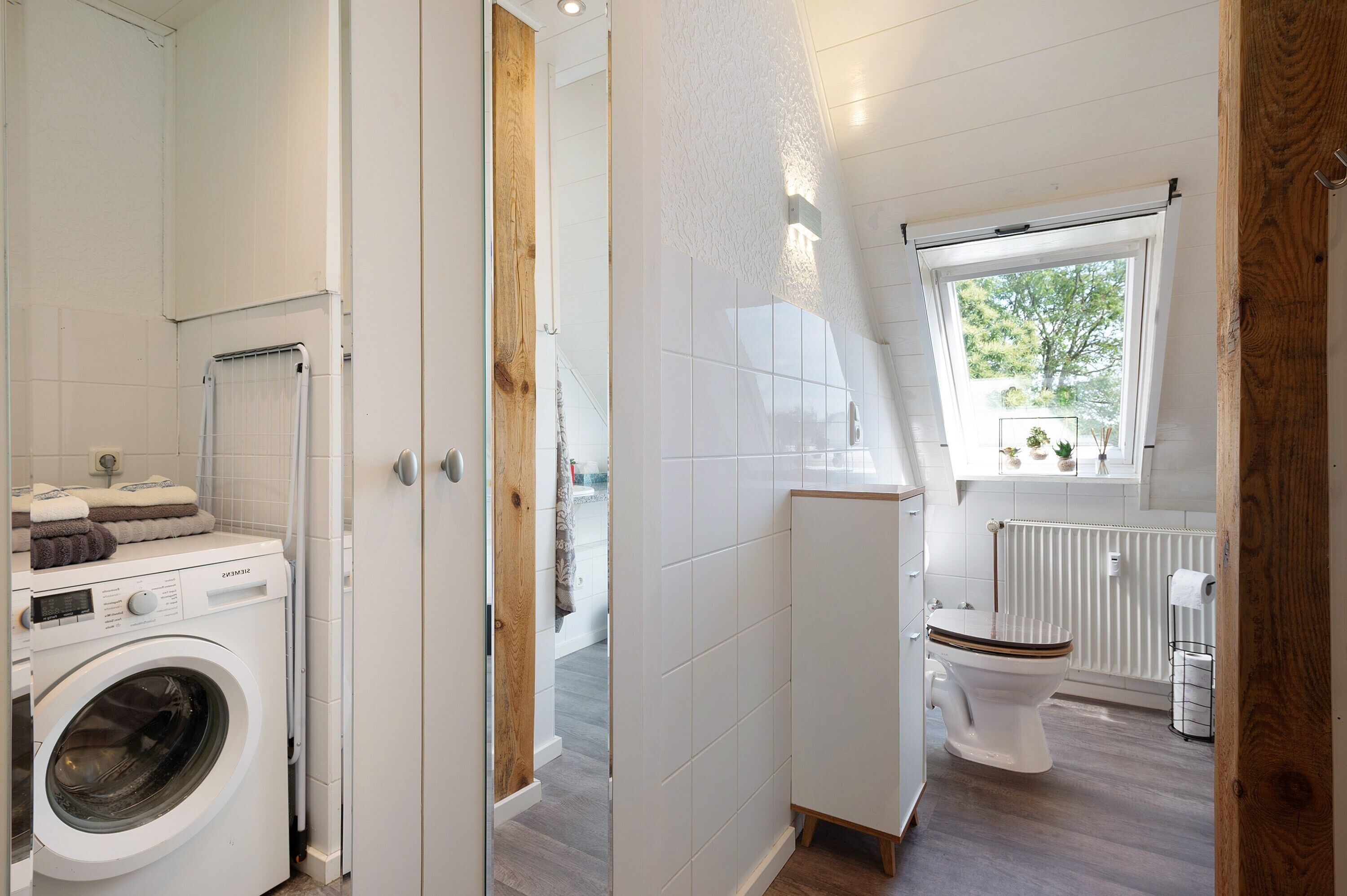 Un baño moderno con lavadora, inodoro y ventana con vistas.