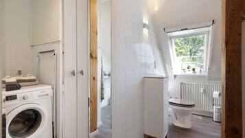 Un baño moderno con lavadora, inodoro y ventana con vistas.