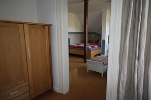 Ein Schlafzimmer mit einem Holzschrank, einem Bett mit gestreifter Bettdecke und einer kleinen Bank.