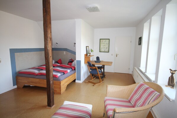 Ein Schlafzimmer mit Bett, Schreibtisch, Schaukelstuhl und Fenster.