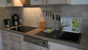 Een moderne keuken met een inbouwfornuis, een spoelbak en een messenhouder.