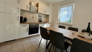 Une cuisine moderne avec des meubles blancs, une table à manger avec des chaises et une fenêtre donnant sur un beau paysage.