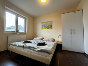 A bedroom with a bed, a window, a radiator, a painting, and a wardrobe. - Holiday Home 'Haus Strandräuber Mit Sauna' with Private Terrace, Private Garden and Wi-Fi (Zierow)