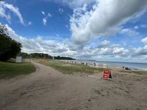 A beach with a sandy path, a sign reading 'ZUM IMBISS,' and a body of water in the background. - Holiday Home 'Haus Strandräuber Mit Sauna' with Private Terrace, Private Garden and Wi-Fi (Zierow)
