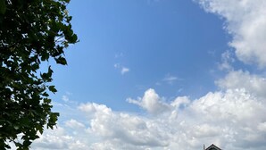 Ländliche Landschaft mit einem Feldweg, der zu einer Häuserreihe führt.