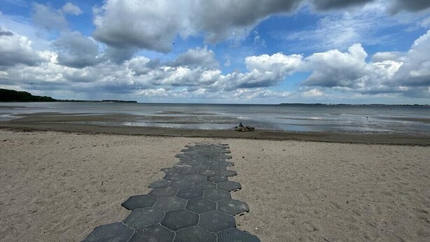 Ein Strand mit einem sechseckig gemusterten Weg, der zum Wasser führt.