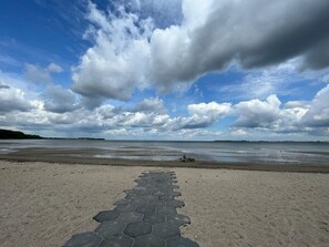 Een strand met een pad met een honingraatpatroon dat naar het water leidt.