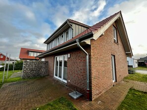 A two-story house with a brick exterior, a sloped roof, and a visible gutter system.