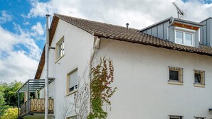 Edifici amb teulada de rajola, balcó amb barana de metall i finestra amb reixatge metàl·lic.