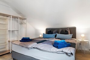 A neatly made bed with a headboard, a side table with a lamp, and a built-in shelving unit.