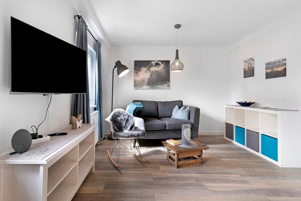 A modern living room with a flat-screen TV, a rocking chair, a coffee table, and a sofa.