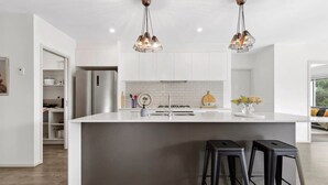 A modern kitchen with a central island, stainless steel appliances, and pendant lighting.
