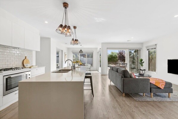 A modern kitchen with white cabinets, a central island, and pendant lighting.