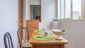 A small dining area with a wooden table, two chairs, and a window with a view of buildings. - Porta Di Mare Apartment With Balcony and A/C (Nardò)