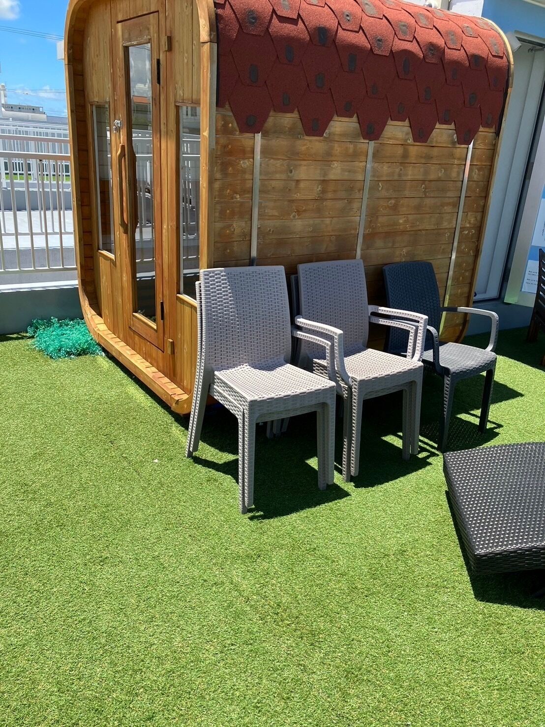 A deck with wicker chairs and a small table, a wooden door, and a red awning.