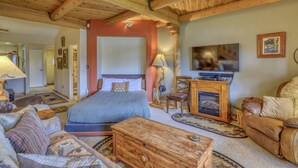 Um quarto aconchegante com cama, móveis de madeira, televisão e lareira.