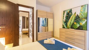 A modern hotel room with a large bed, a wooden wardrobe, a mirror, and a painting of leaves on the wall. - Maisonnette & Pool Ta'cenc Sannat Gozo (Sannat)